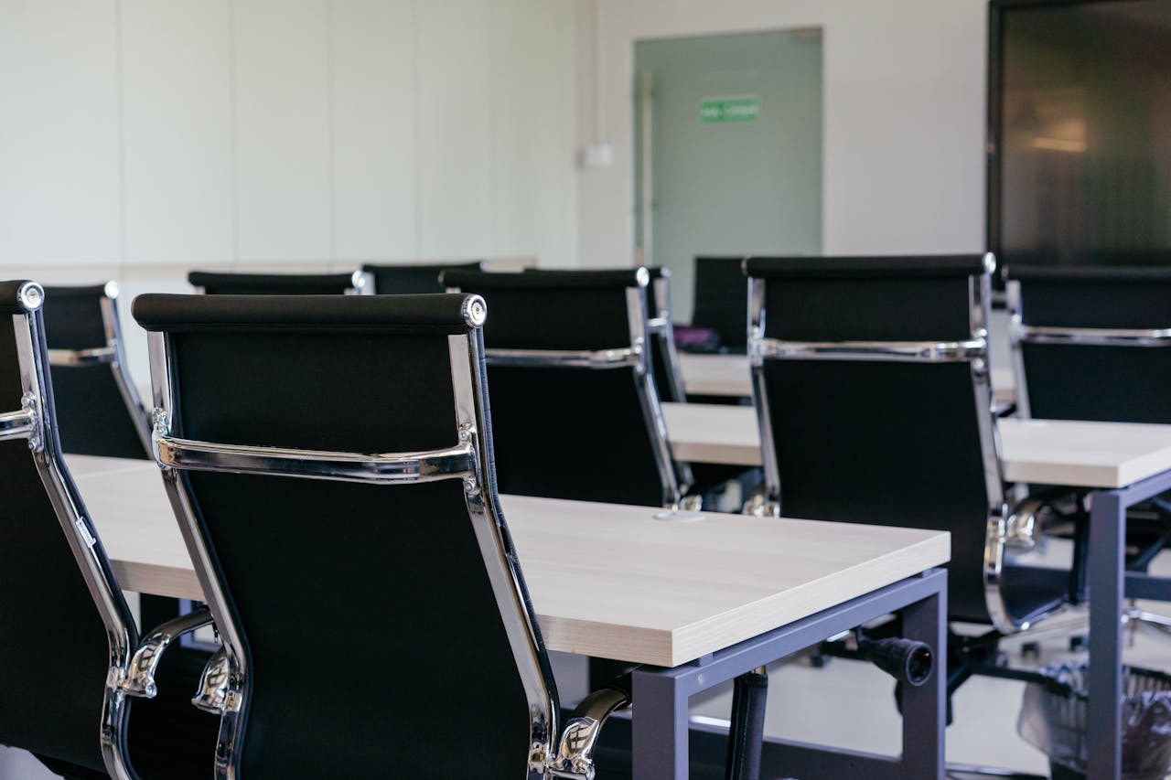 Sleek modern conference room with black chairs and white desks, suitable for business meetings.